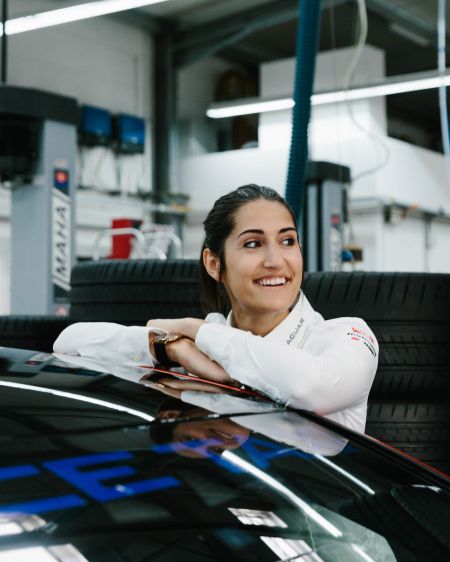 Racing driver Celia Martin leans against her race car in the garage