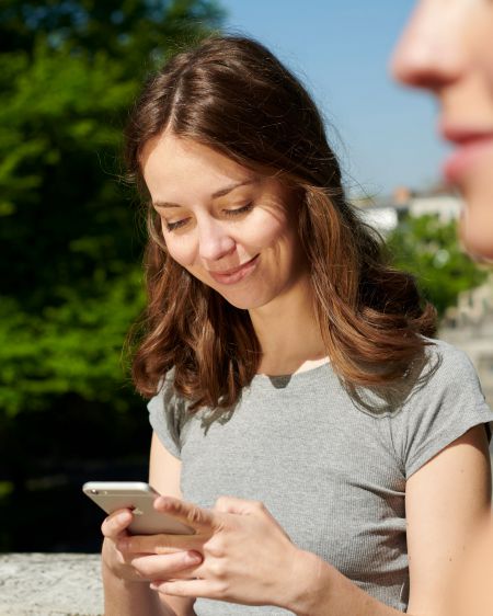 Young woman looking at mobile phone, and in the foreground is another woman