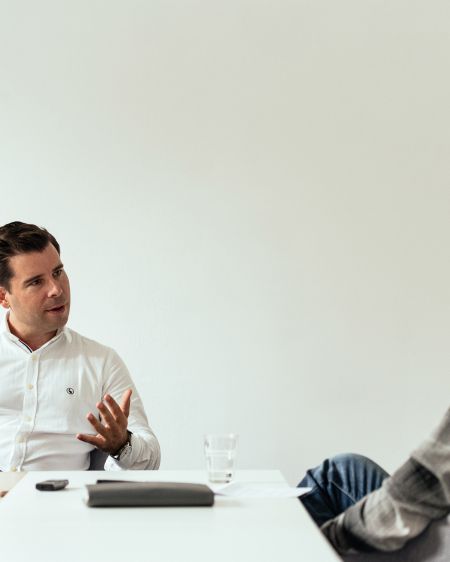 Felix Haas sits at the table, opposite Stefan Ruzas, who listens to him attentively