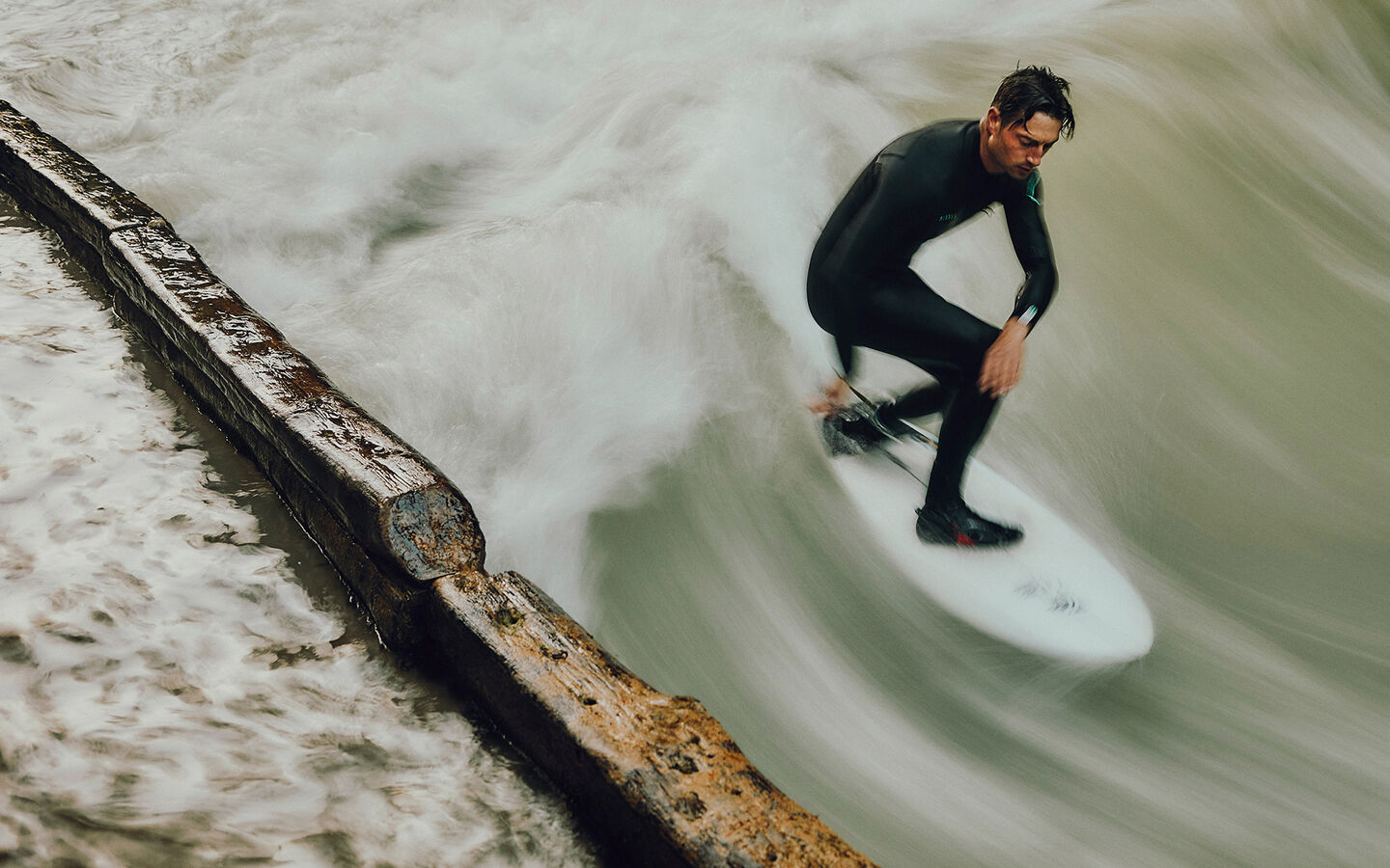 River surfing at the Eisbach in Munich Sebastian Kuhn stands on his surfboard and river surfs at the Eisbach