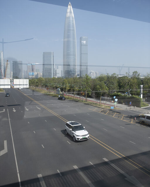 Discover Shenzhen: City trip with the Range Rover Sport Plug-in Hybrid White Range Rover Sport Plug-in Hybrid drives multi-lane road in front of Shenzhen city skyline
