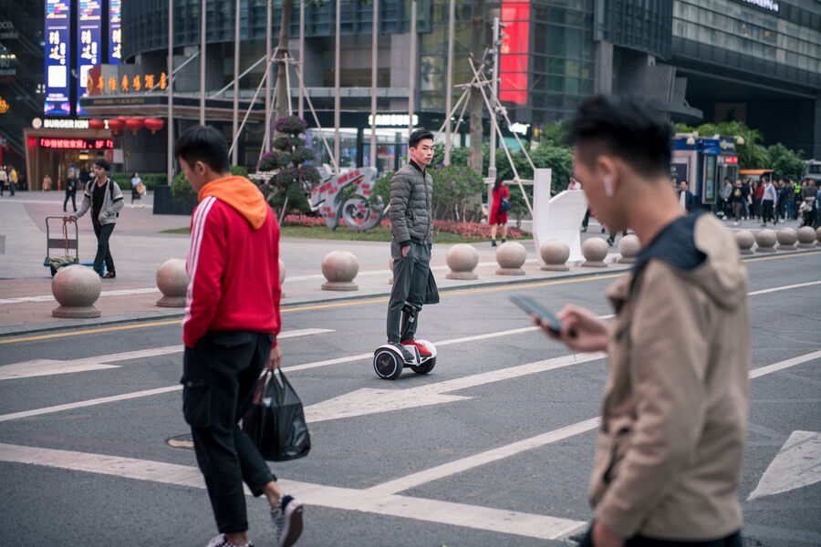 Range Rover Sport Plug-in Hybrid test drive: On the road in the Chinese high-tech city of Shenzhen Snapshot of several pedestrians and a hoverboard driver on road in Shenzhen