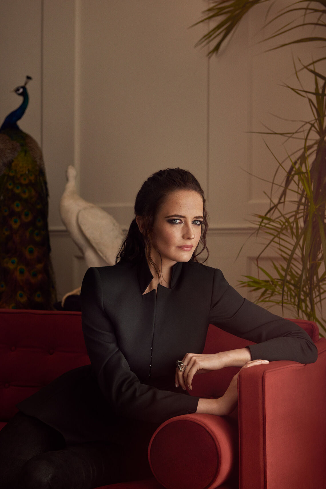Behind the scenes: Eva Green beim Werbedreh für den Jaguar I-PACE Eva Green sitzt mit schwarzer Bluse auf rotem Sofa