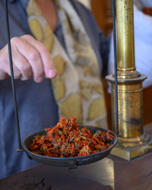 Woman weighing red dried flowers on a mechanical scale