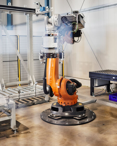 Orange-coloured industrial robot stands in the production hall of the company Main-Automation