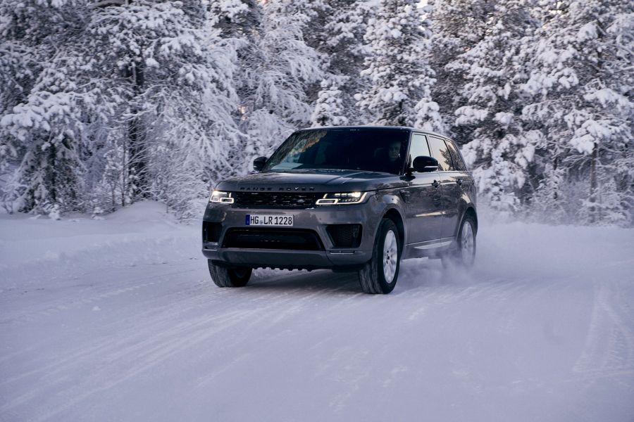 Dog sledding in Lapland: Visiting a husky farm Dark grey Range Rover Sport drives through snowy forest in Lapland