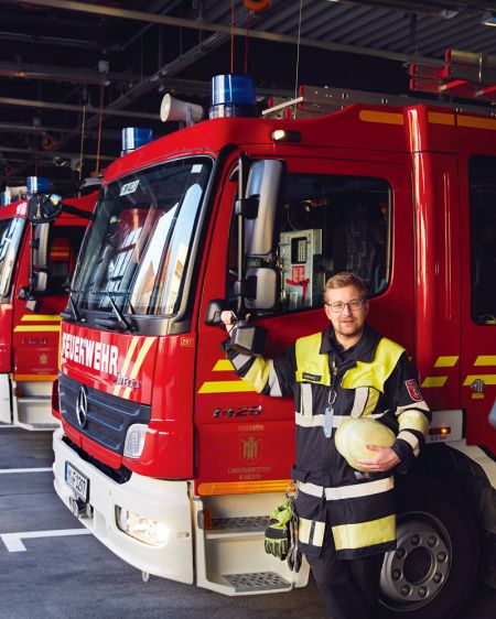 Martin Lammers, volunteer at the Munich fire department, stands in front of a fire engine