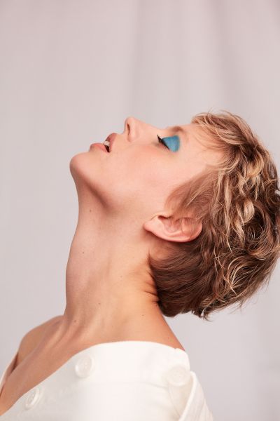 LUDWIG BECK Beauty: Covershooting für die Frühjahr-/Sommerausgabe 2020 Seitliche Aufnahme einer jungen Frau mit kurzen Haaren und blauem Lidschatten vor weißem Hintergrund
