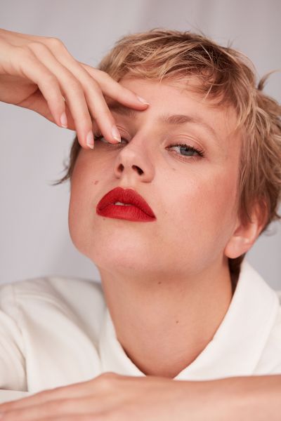 LUDWIG BECK Beauty: Covershooting für die Frühjahr-/Sommerausgabe 2020 Nahaufnahme einer jungen Frau mit kurzen Haaren und roten Lippen vor weißem Hintergrund