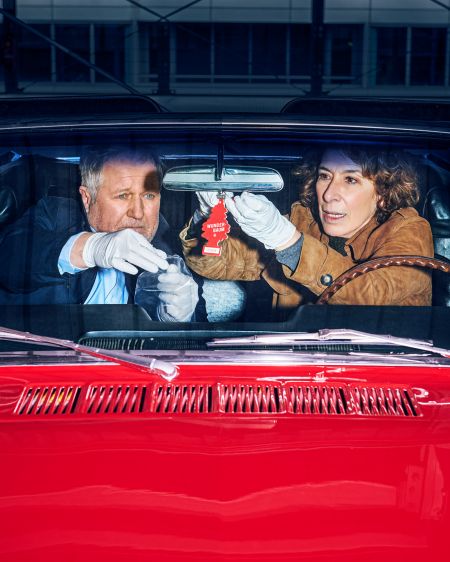 Harald Krassnitzer and Adele Neuhauser in the frontseats of a red Mustang