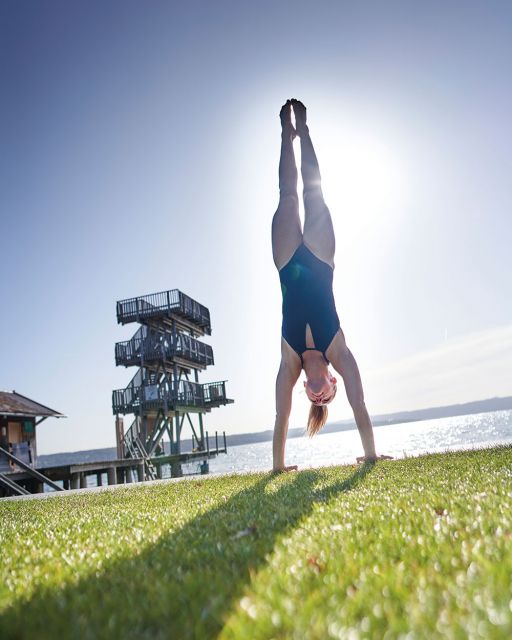 Interview Iris Schmidbauer Ammersee Iris Schmidbauer macht einen Handstand vor einem Sprungturm am Ammersees