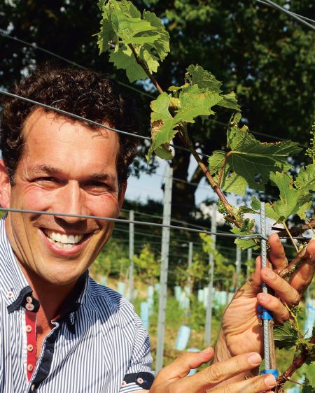 Portrait photo of winemaker Uli Ernst in front of slope with vines