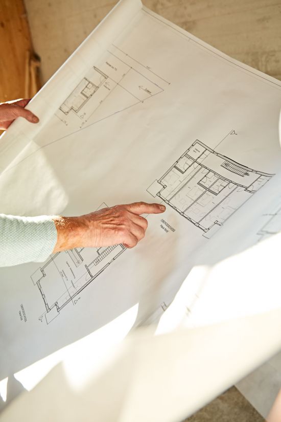 Hand points to building plan Anderl and Karl-Michael Friedinger in an interview for SeeMagazin