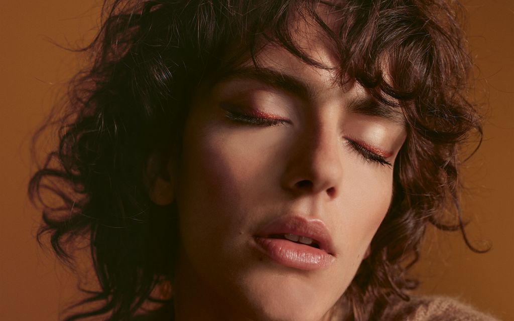 LUDWIG BECK Beauty: Cover shoot for the christmas 2020 issue Young woman with brown curls with closed eyes on the lids is a copper colored eyelid line