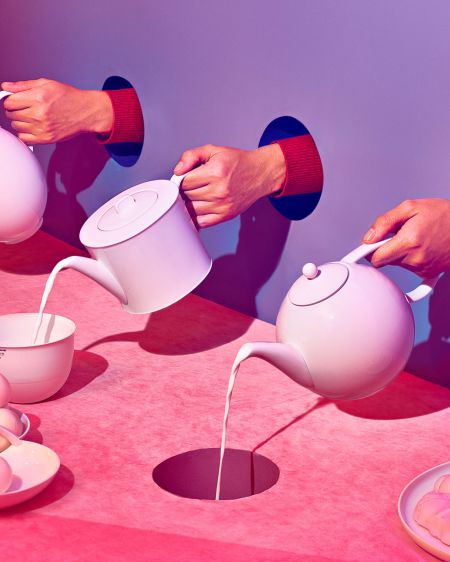 Hands hold three coffee pots and pour liquid from them into porcelain vessels