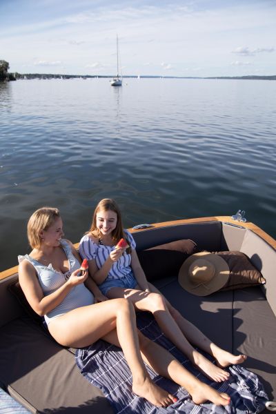 E-boating on Lake Ammersee for SeeMagazin 2021 Two young women sitting in electric boat eating watermelon