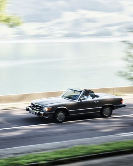 Vintage convertible drives along the lake on a country road