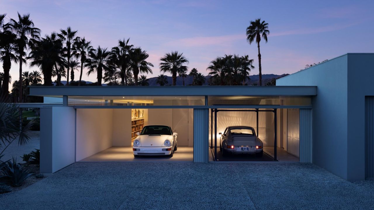 Modernes Garagenhaus bei Abenddämmerung mit zwei klassischen Porsches und Palmen im Vordergrund Modernes Garagenhaus bei Abenddämmerung mit zwei klassischen Porsches und Palmen im Vordergrund