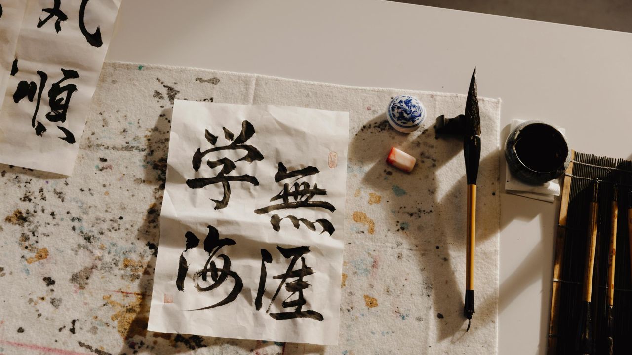 Close-up of a table with calligraphy brushes, ink, and folded paper with Chinese characters Close-up of a table with calligraphy brushes, ink, and folded paper with Chinese characters