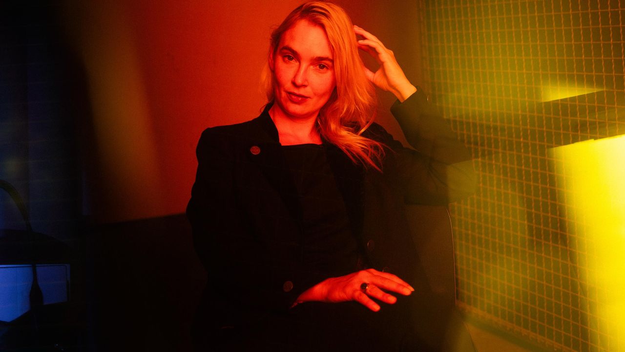 Portrait of a woman in a dark suit, sitting in a room with intense red and yellow lighting Portrait of a woman in a dark suit, sitting in a room with intense red and yellow lighting