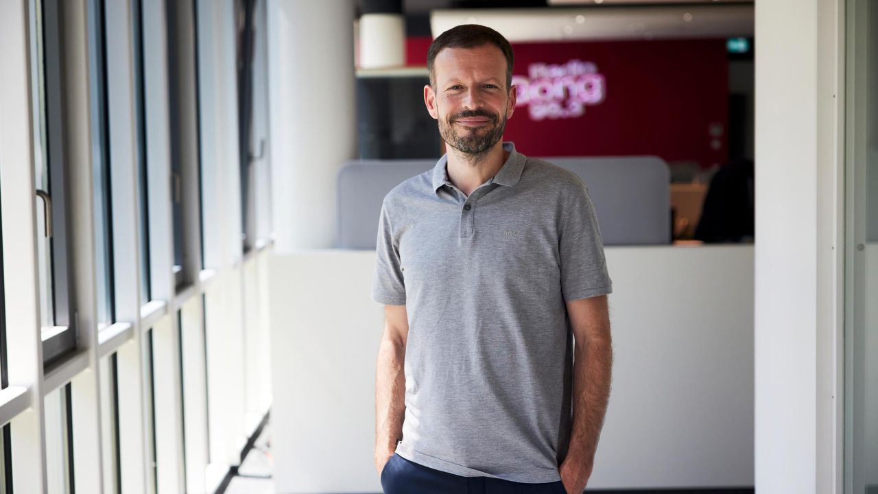 Portrait of a man in a gray polo shirt, standing in a modern, bright office hallway at Radio Gong 96.3. Portrait of a man in a gray polo shirt, standing in a modern, bright office hallway at Radio Gong 96.3.